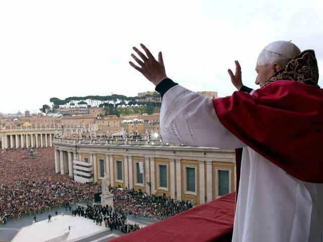 The Pope stands on the balcony and waves to the crowd in St. Peter's Square.