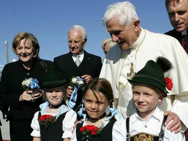 Pope Benedict XVI  stands with three children in traditional clothing next to Chancellor Angela Merkel and the Bavarian Governor Edmund Stoiber.