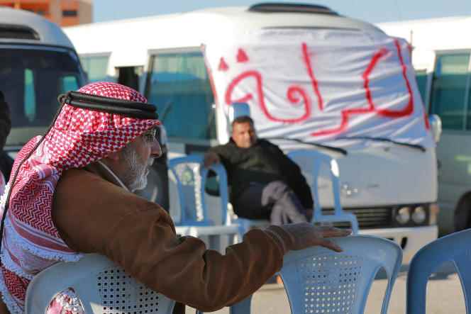 Jordanian bus drivers sit next to a banner bearing a slogan that reads 'dignity' in Arabic, on December 16, 2022, in Jordan's southern province of Maan, as they continue a strike started earlier this month to protest rising fuel prices.