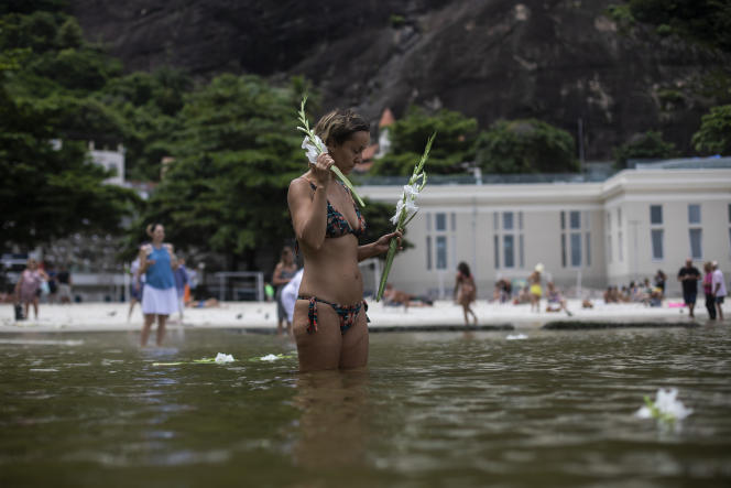 A woman makes an offering of flowers to the sea goddess Yemanja, Saturday, Dec. 31, 2022, at Urca Beach, Rio de Janeiro, Brazil, in exchange for a blessing for the New Year.  One certainty, already: in Brazil, January 1, 2023 sees the return to power of former head of state Lula and the departure of far-right president Jair Bolsonaro.