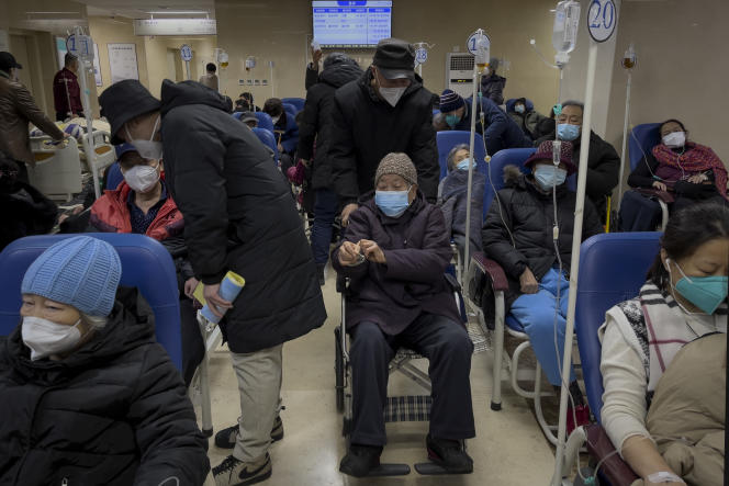 A man pushes an elderly woman past patients receiving intravenous drips in a hospital's emergency department, Tuesday, Jan. 3, 2023. As the virus continues to plague China, global organizations and governments have called on the country to start sharing its data, while others criticized the current numbers, calling them insignificant.
