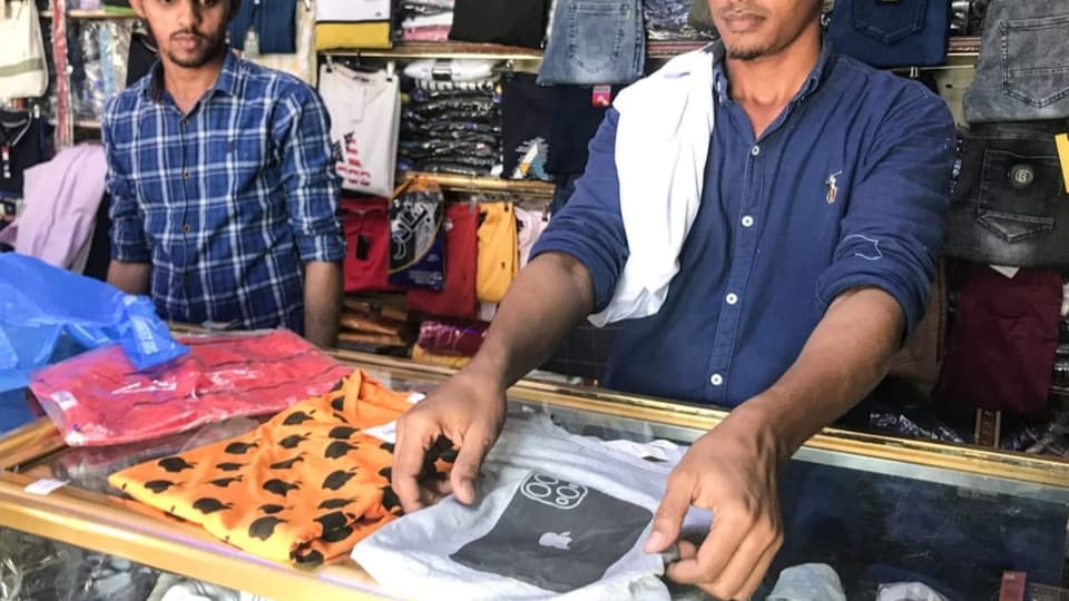 A seller presents a T-shirt with an iPhone pictured on it.