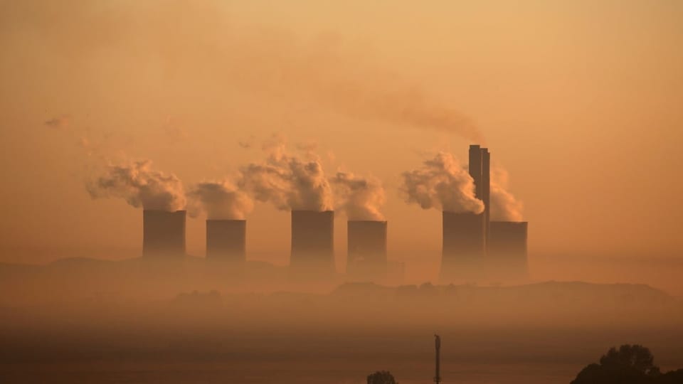 Six power plant towers that emit a lot of steam.  They are coal-fired power plants in South Africa