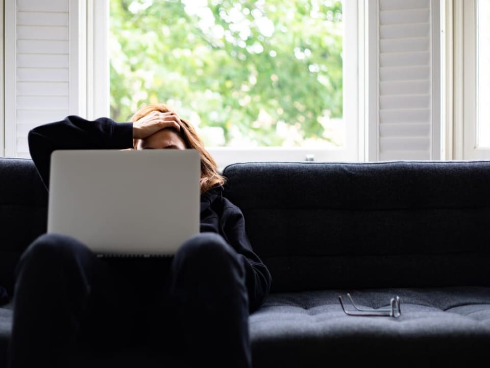 Stressed woman sitting on the sofa with a laptop on her lap