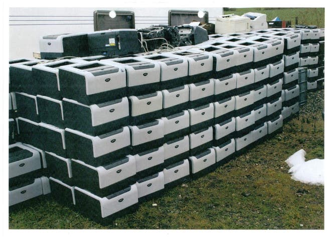 Discarded printers from the Department of Justice are stored in a meadow.