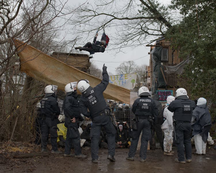 Police officers examine the trees between which a demonstrator is hanging on a truss.