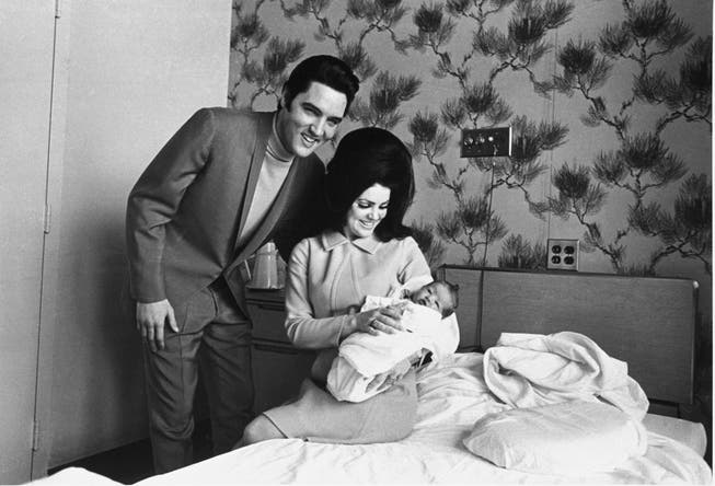 Lisa Marie Presley poses for her first photograph on her mother Priscilla's lap on February 5, 1968 with her father Elvis Presley.