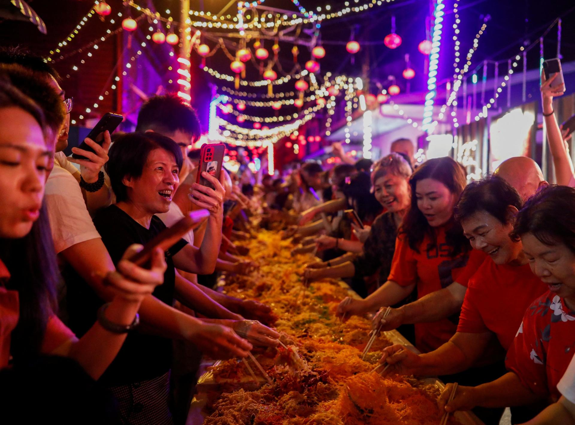 Villagers prepare to throw yusheng (raw fish) during a 