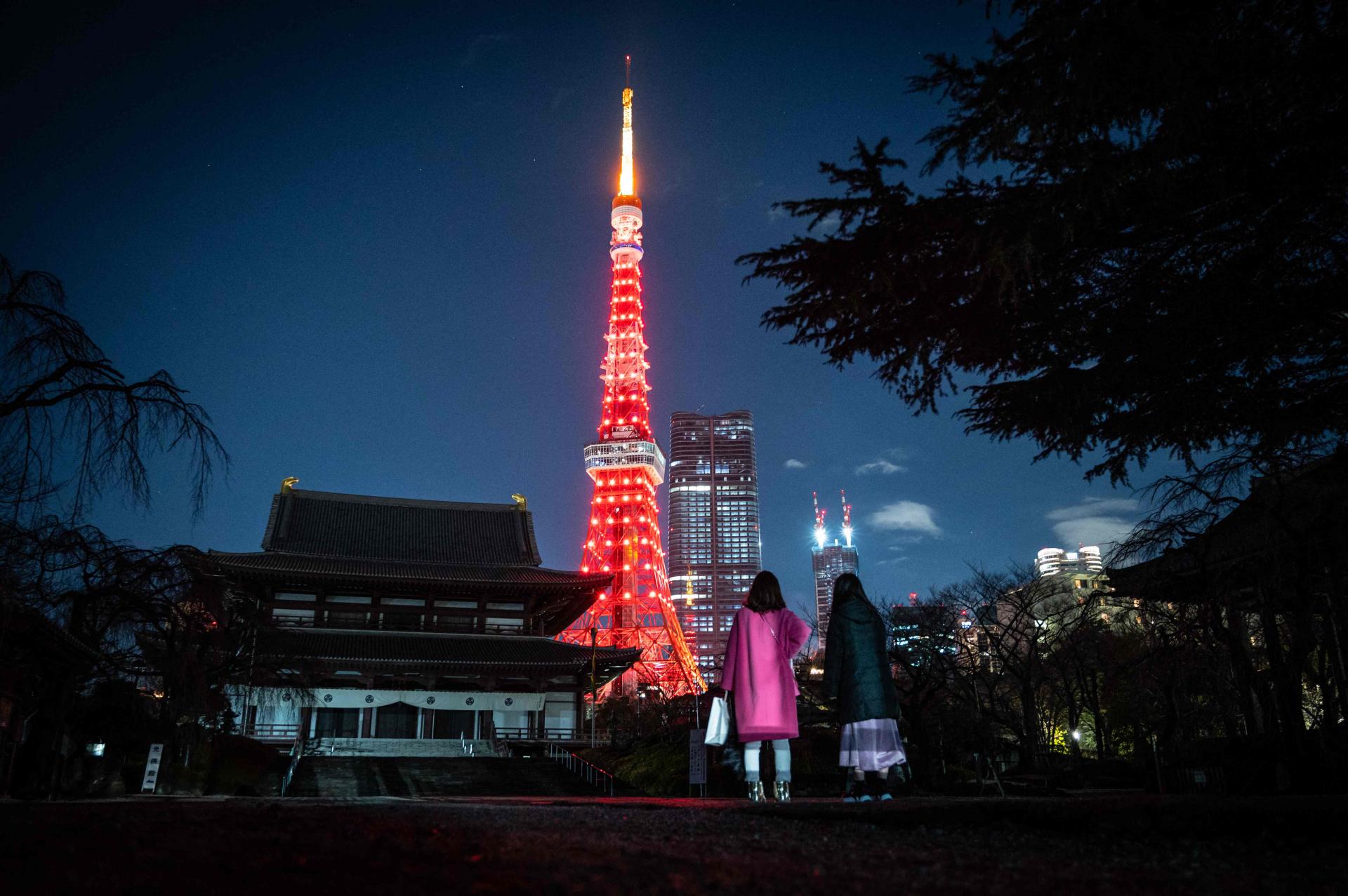 In front of the Zojo-ji temple, as the Tokyo Tower is illuminated in red to celebrate the Chinese New Year, in Tokyo on January 21, 2023. 