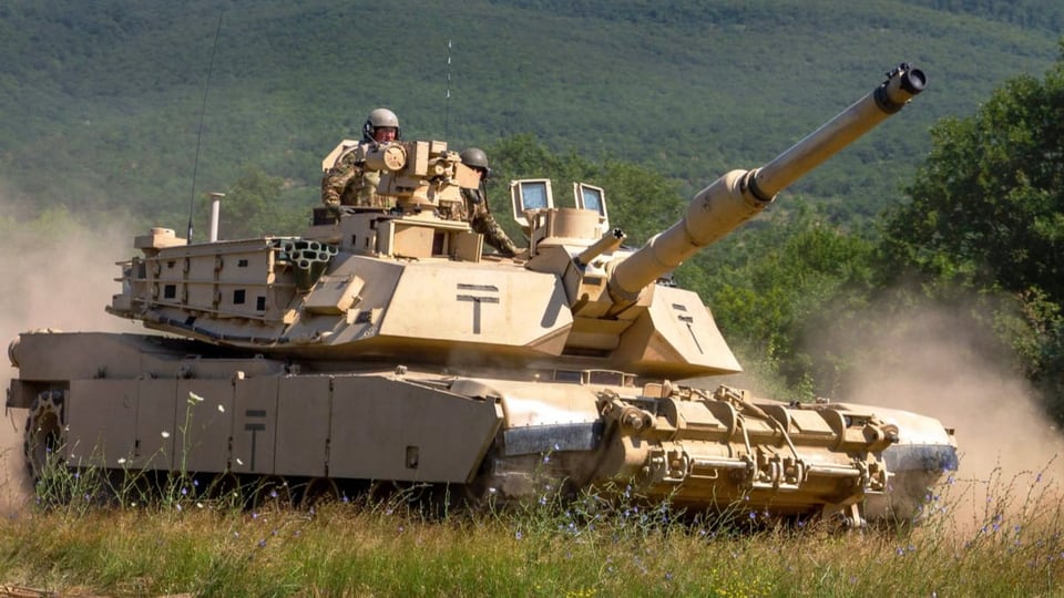 The M1 Abrams is driven by a soldier in a field. 