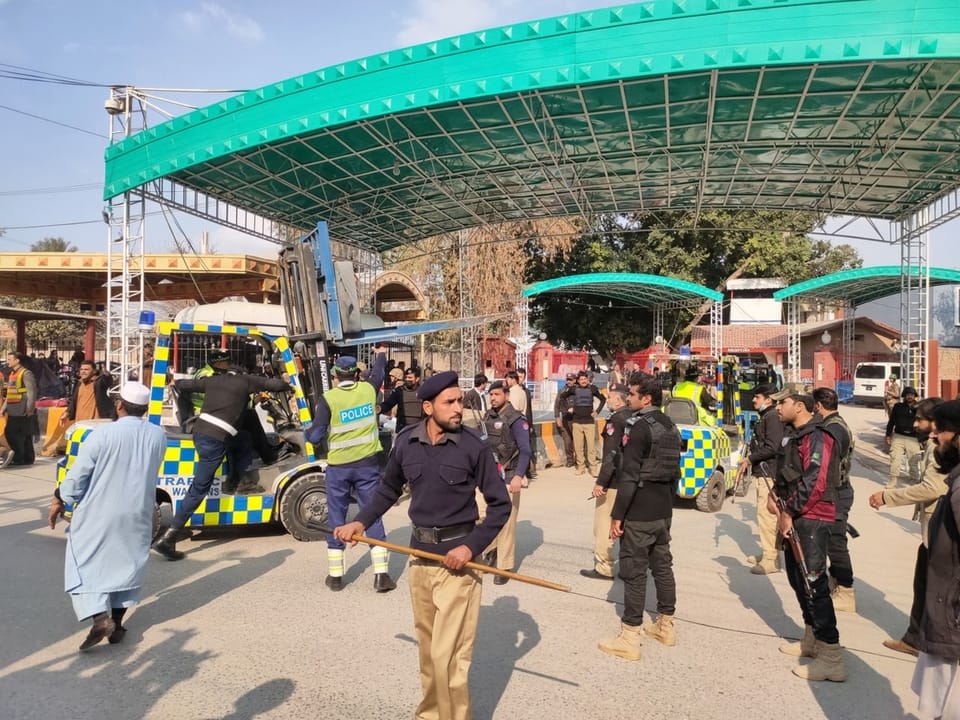 Pakistani security officials stand guard while an ambulance drives the victims away. 