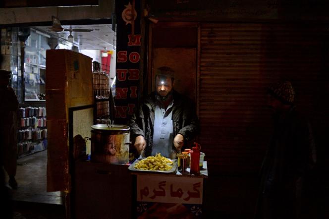 A trader frys potatoes at his market stall during a nationwide power outage, in Islamabad on January 23, 2023.
