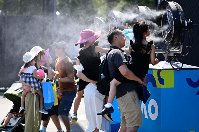 A family of spectators cool off in front of misting fans, in Melbourne Park, Australia, Tuesday, January 17, 2023.
