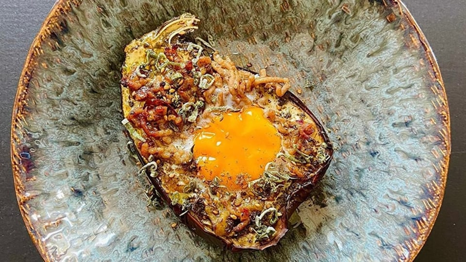 Dukkah on an aubergine with an egg from the oven.