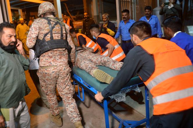 Volunteers carry an injured soldier to a hospital after an attack on a police compound in Karachi on February 17, 2023.