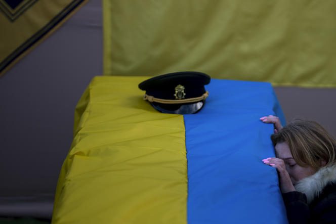 The wife of a Ukrainian soldier who died in combat kneels before his coffin during the funeral, in Tarassivka (Ukraine), February 15, 2023.