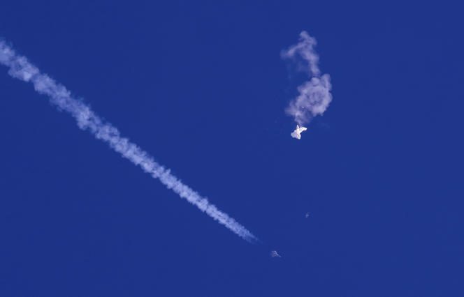 The remains of the large balloon shot down by the United States drift over the Atlantic Ocean, just off South Carolina, with a fighter jet and its contrail below, February 4, 2023.