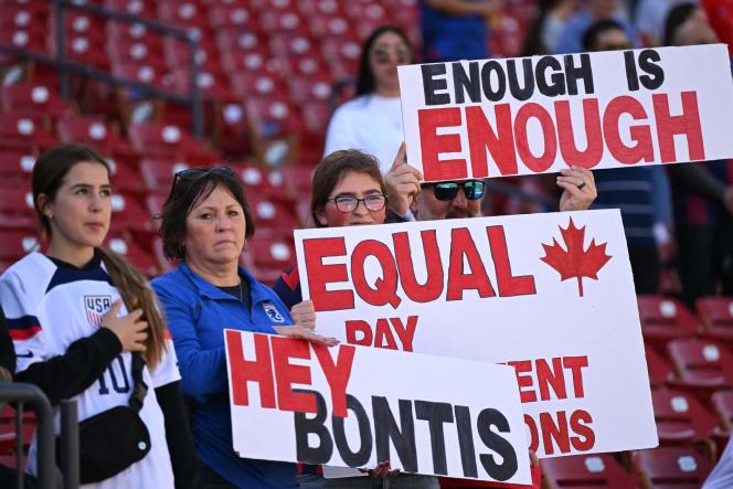 Canada's national team supporters hold signs against gender inequality during a game against Japan in Frisco, Texas on February 22, 2023.