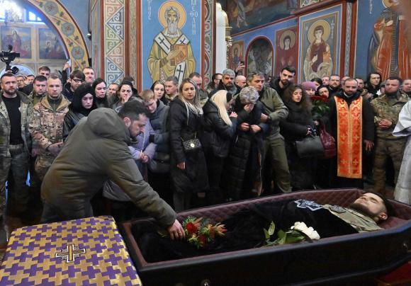 Volodymyr Zelensky lays a bouquet in Dmytro Kotsiubailo's coffin.