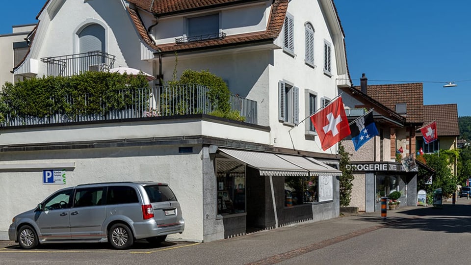 Street view with shops in older houses, Swiss and Aargau flags are waving.