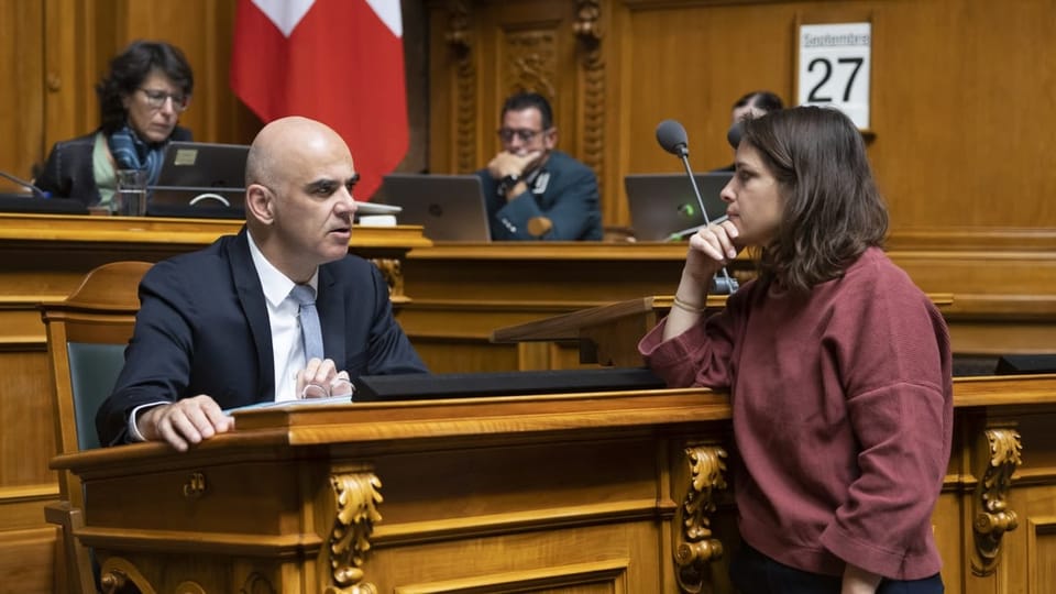 Alain Berset and Mattea Meyer speak together in Parliament.