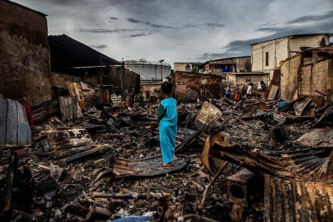 A child in the middle of homes charred by the fire, Friday, March 3, of a fuel depot in Plumpang, Indonesia. 