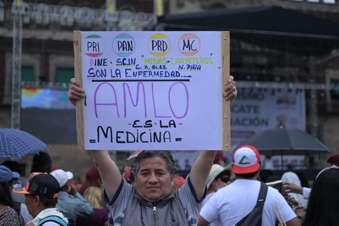 A supporter of President Andres Manuel Lopez Obrador holds a sign citing opposition parties that 'are the disease, AMLO is the medicine', during the protest in favor of the Mexican president, in the Zocalo square, Mexico City, on 18 March 2023.  