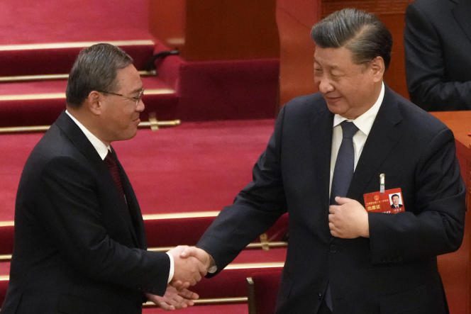 China's new premier, Li Qiang (left), shakes hands with President Xi Jinping, in Beijing, Saturday, March 11, 2023.