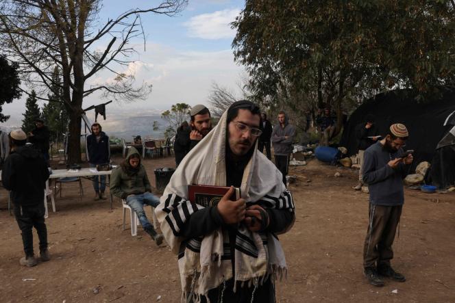Israeli settlers pray in the former settlement of Homesh, west of the West Bank city of Nablus, on December 30, 2021.
