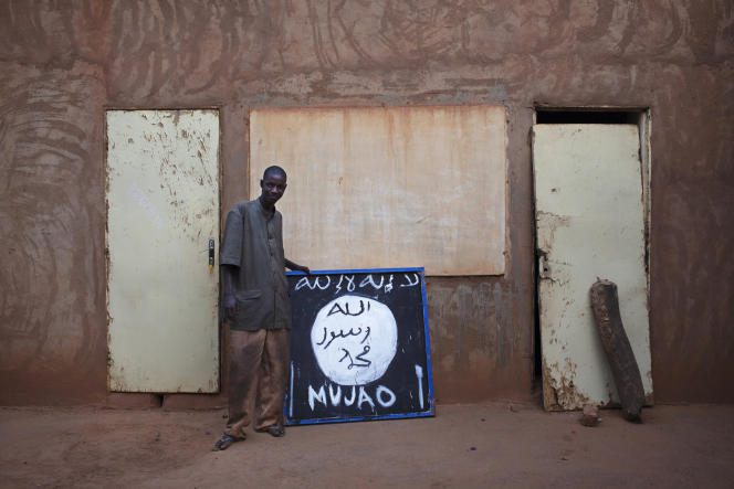 A Malian poses in front of a sign of the Movement for Unity and Jihad in West Africa (Mujao), in Douentza, in January 2013.