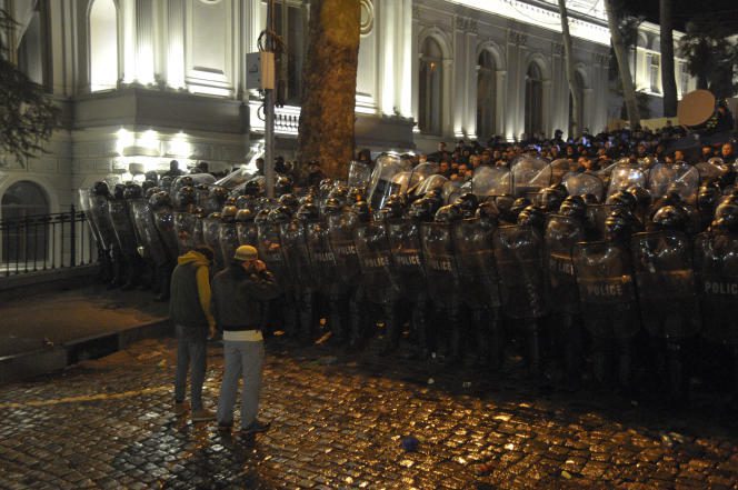 Two demonstrators face a police cordon, near the Georgian Parliament, in Tbilisi, Tuesday March 7, 2023.