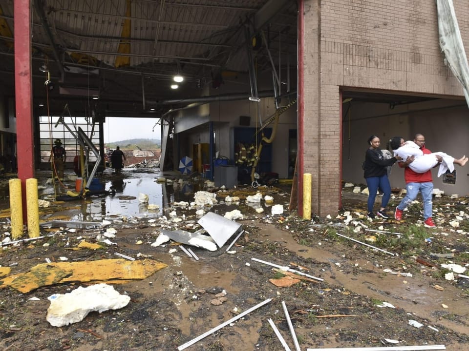 People are carried away from a tornado-devastated site.