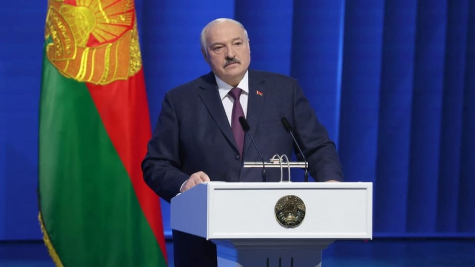 Lukashenko at the lectern in front of a Belarusian flag.