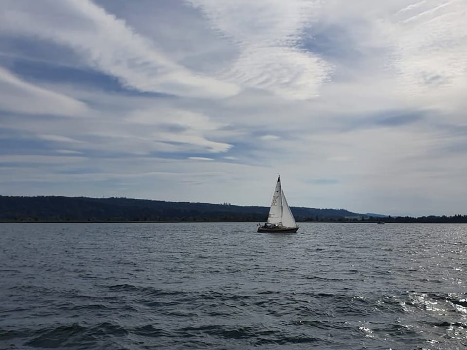 Sailing ship on a lake under a partly cloudy sky