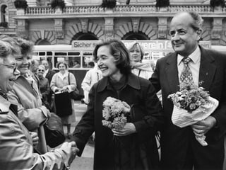 Elisabeth Kopp shakes hands with a woman, flanked by husband Hans W. Kopp.