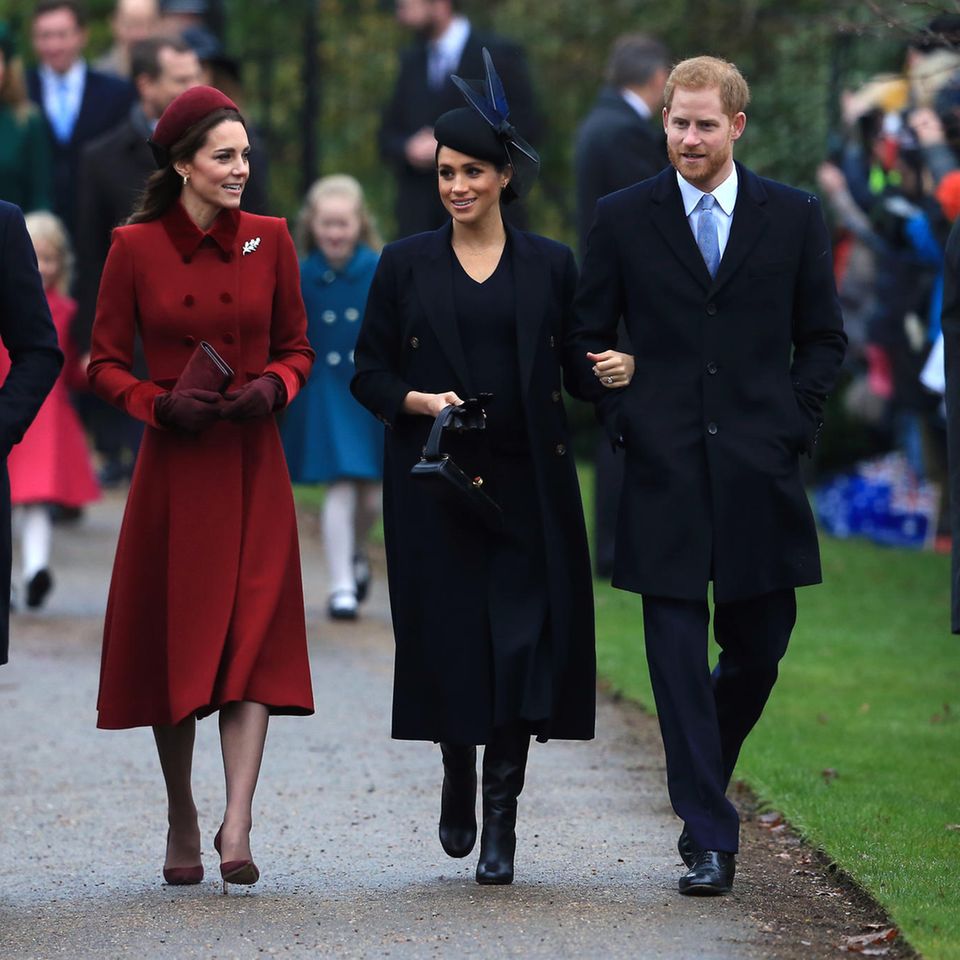 Meghan's first Christmas as Duchess of Sussex.  In a dark blue coat, she doesn't stand out next to Kate in burgundy and next to Harry and William in dark blue. 