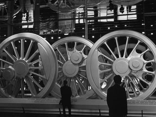 Visitors examine huge steel wheels for steam locomotives.