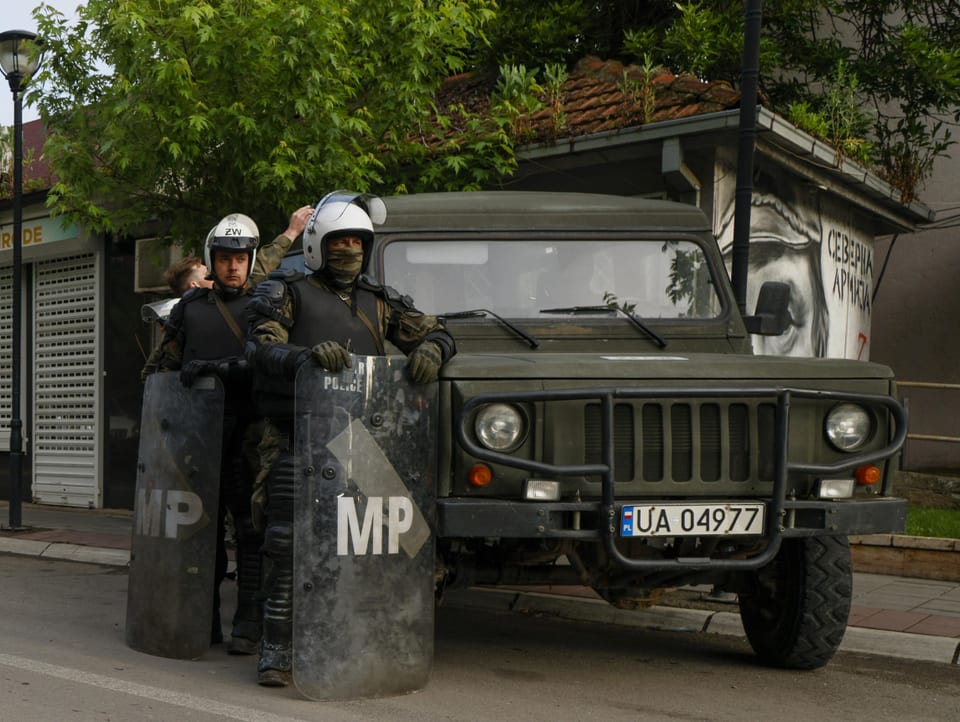 Soldiers in demonstration gear stand next to a military SUV.