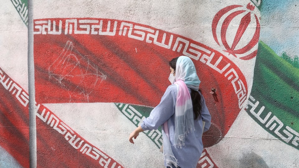 Woman in front of a mural with the Iranian flag.
