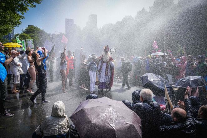 Extinction Rebellion protesters face a water cannon, in The Hague, Saturday, May 27, 2023.  