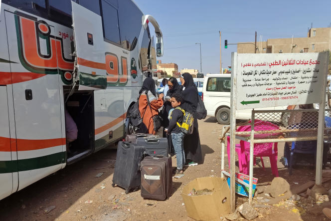 Sudanese with their luggage at a bus stop in Khartoum on May 8, 2023.