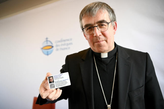 Bishop Alexandre Joly shows his identity card during a press conference as part of the Conference of Bishops of France, in Paris, May 10, 2023.