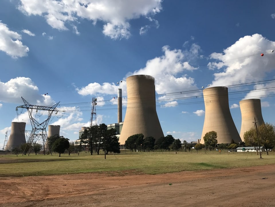 View of a coal-fired power station in South Africa.  There are several cooling towers next to each other.