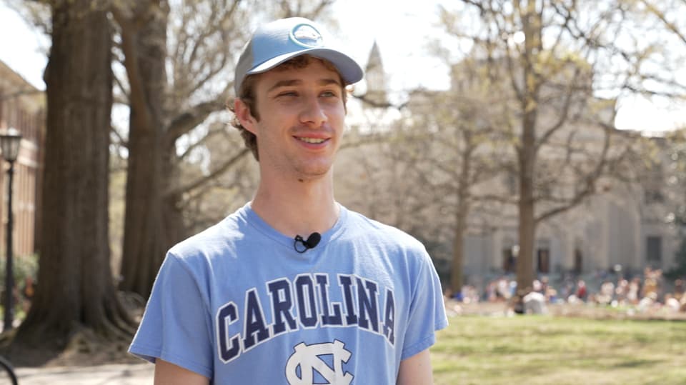 Young white man wearing a Uni Carolina shirt looks past the camera