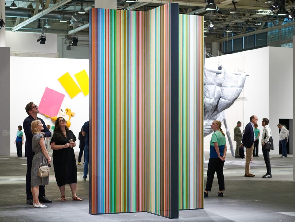 A tower of different colored stripes is admired by visitors to Art Basel.