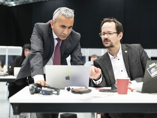 Mustafa ATici bends over a laptop;  Balthasar Glättli is sitting next to him.  The two talk to each other