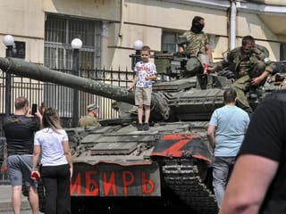 Rostov-on-Don: A child poses for a photo on a tank with the inscription 'Siberia' while soldiers from the Wagner group of mercenaries block a road in downtown Rostov-on-Don (24.6.23)-