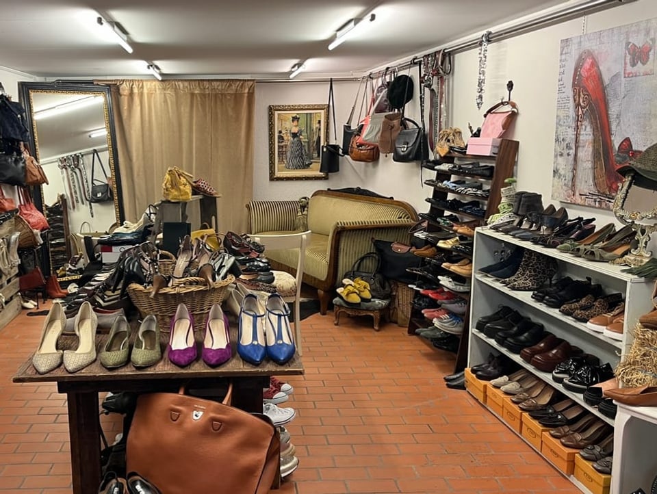 The shoe stall photographed from the front.  Lots of different colored shoes, shoe pictures on the wall and a sofa.