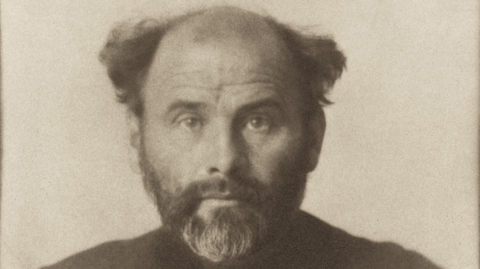 Historical photograph of a balding old man with his hair sticking out to the sides.e