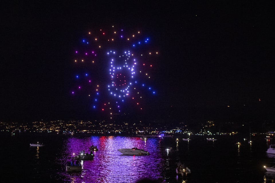 A lion made of points of light is enthroned above Lake Zurich.